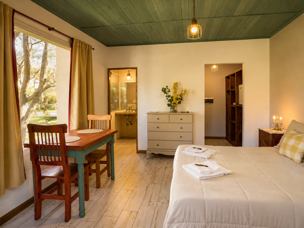 Ambiente de la Suite 9 con cama matrimonial y mesa para dos