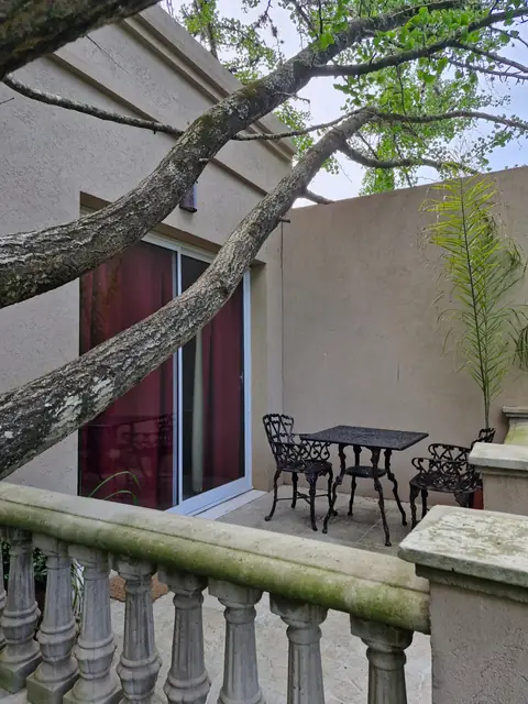 Terraza privada con mesa de hierro bajo los árboles